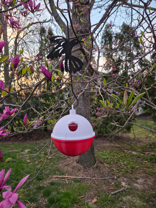 Fishing Bobber Bird House hanging from a hummingbird hanger in a blooming pink magnolia tree