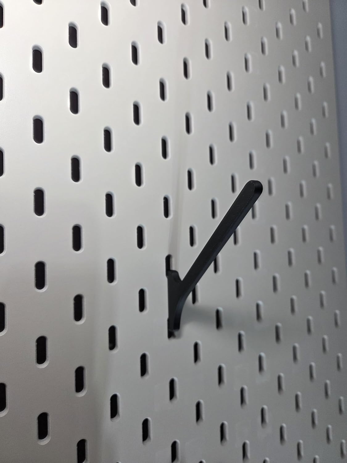 Black angled spool mount clipped into a white IKEA SKADIS pegboard