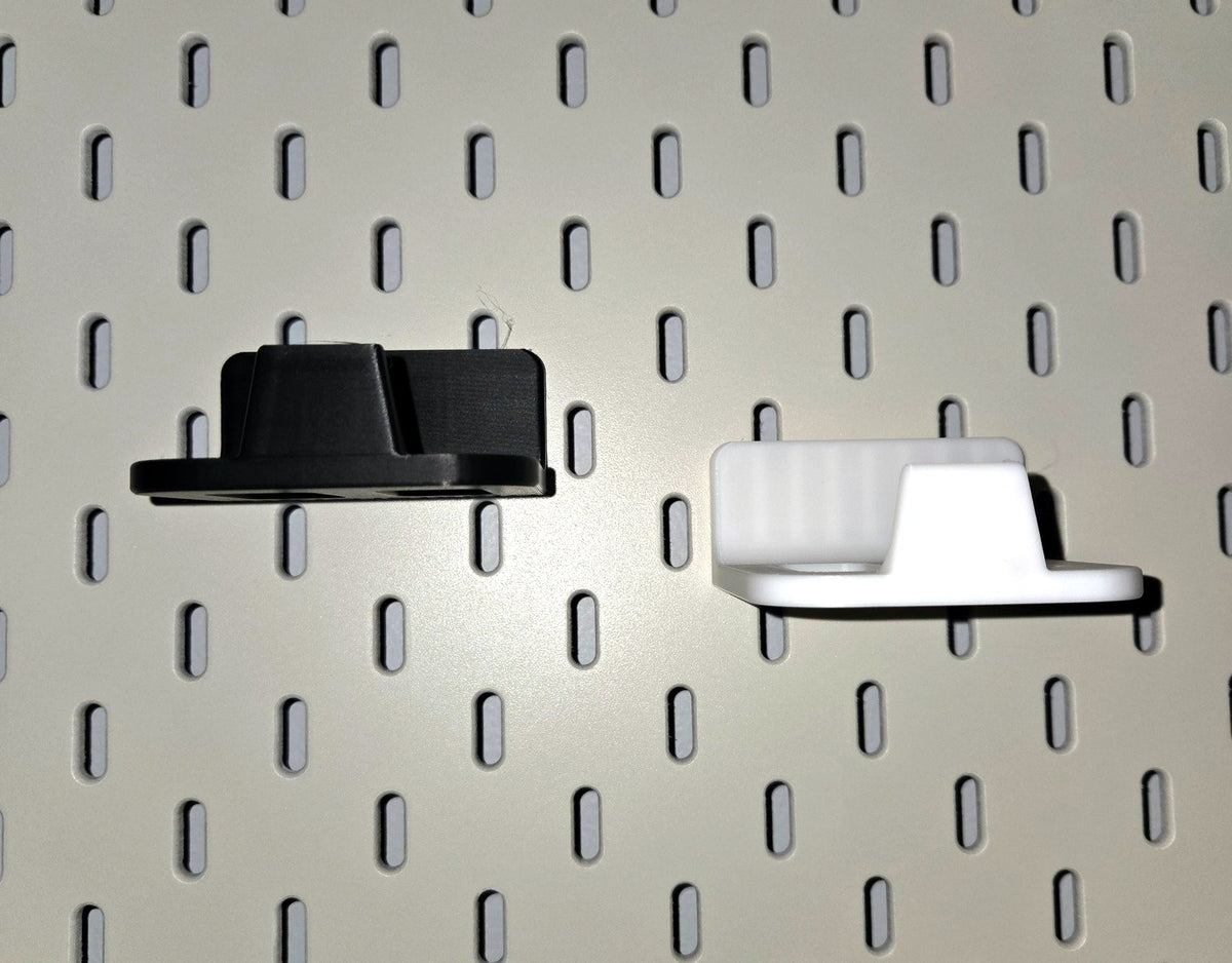 Black and white game controller holders side by side on a pegboard