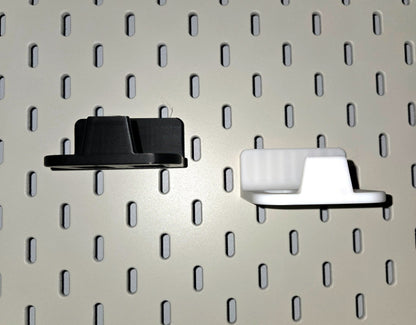 Black and white game controller holders side by side on a pegboard
