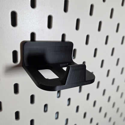 Close-up of the black controller holder hooked into a pegboard, open tray with raised front lip